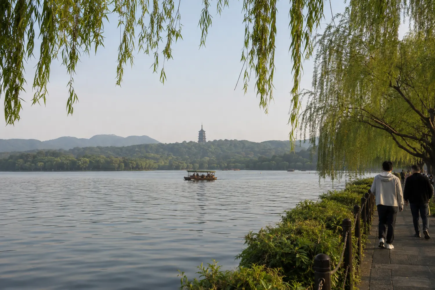 Tourist view of West Lake in Hangzhou with willow trees, a sightseeing boat and distant pagoda